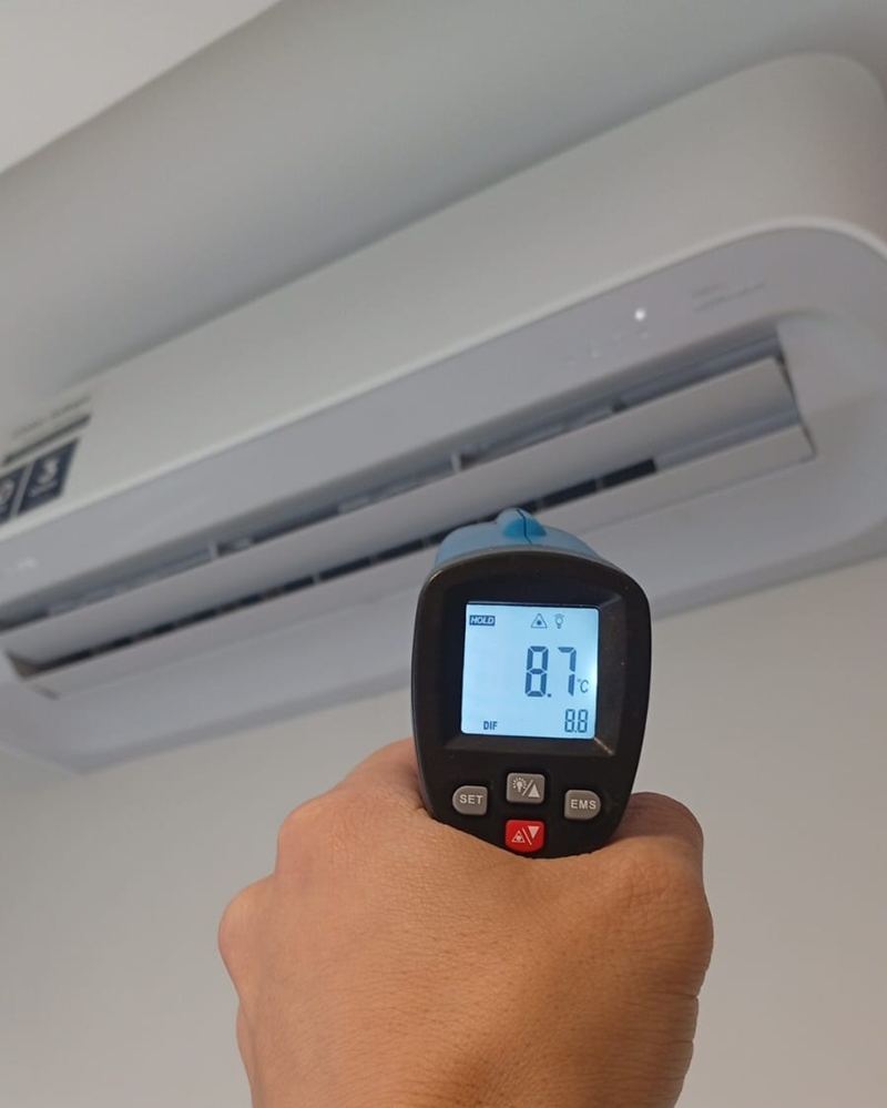 Técnico medindo a temperatura de saída do ar-condicionado com termômetro digital